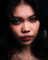 Close-up, vertical shot of a person's face with red lips, dramatic lighting, and visible skin texture.