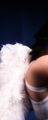 A person's bare shoulder and arm with a white strap, next to large white feathers against a dark background.