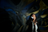 Dark abstract image of textured surfaces with blue and yellow light, and a dark silhouette on the right.
